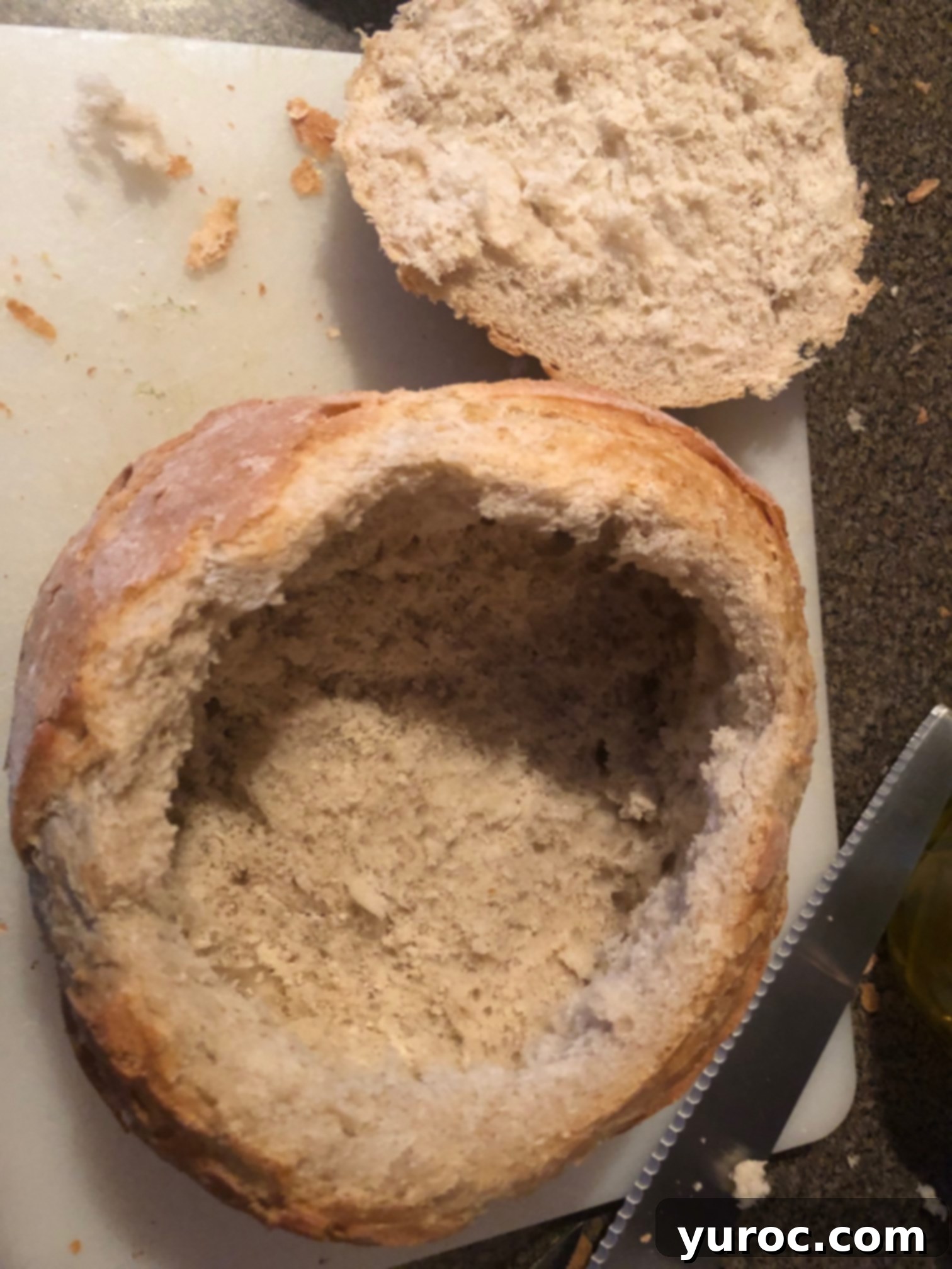 Tuscan Panzanella Pasta Soup 4 The inside of a sourdough loaf is being scooped out with a spoon, creating a hollow bread bowl.
