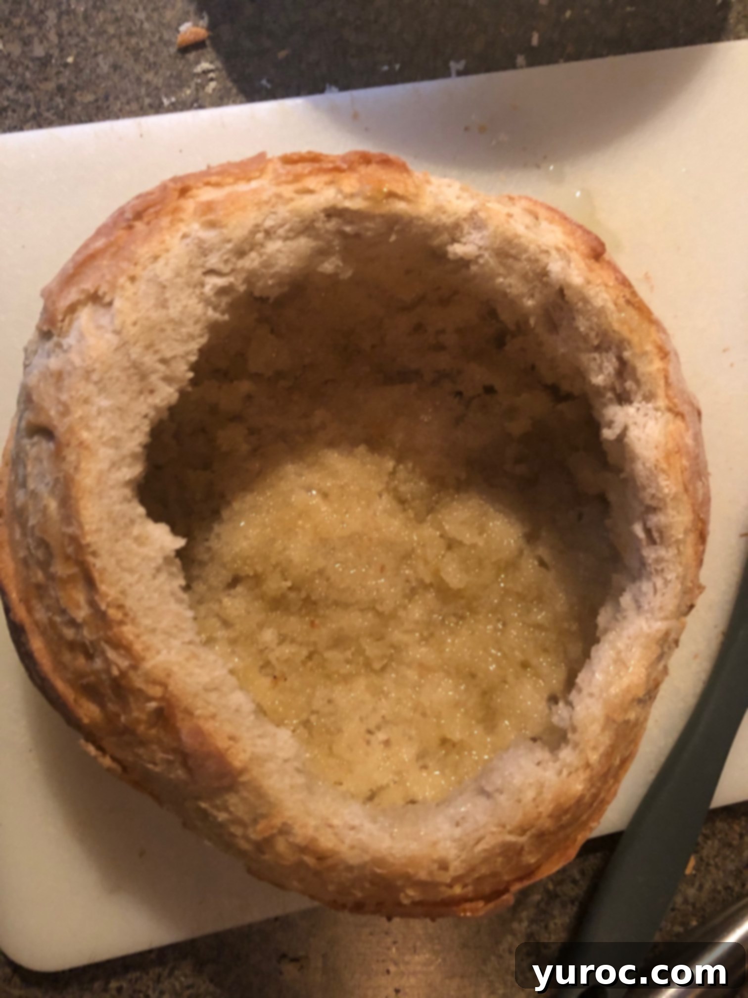 Tuscan Panzanella Pasta Soup 5 Olive oil is being brushed onto the inside of a hollowed-out sourdough bread bowl.
