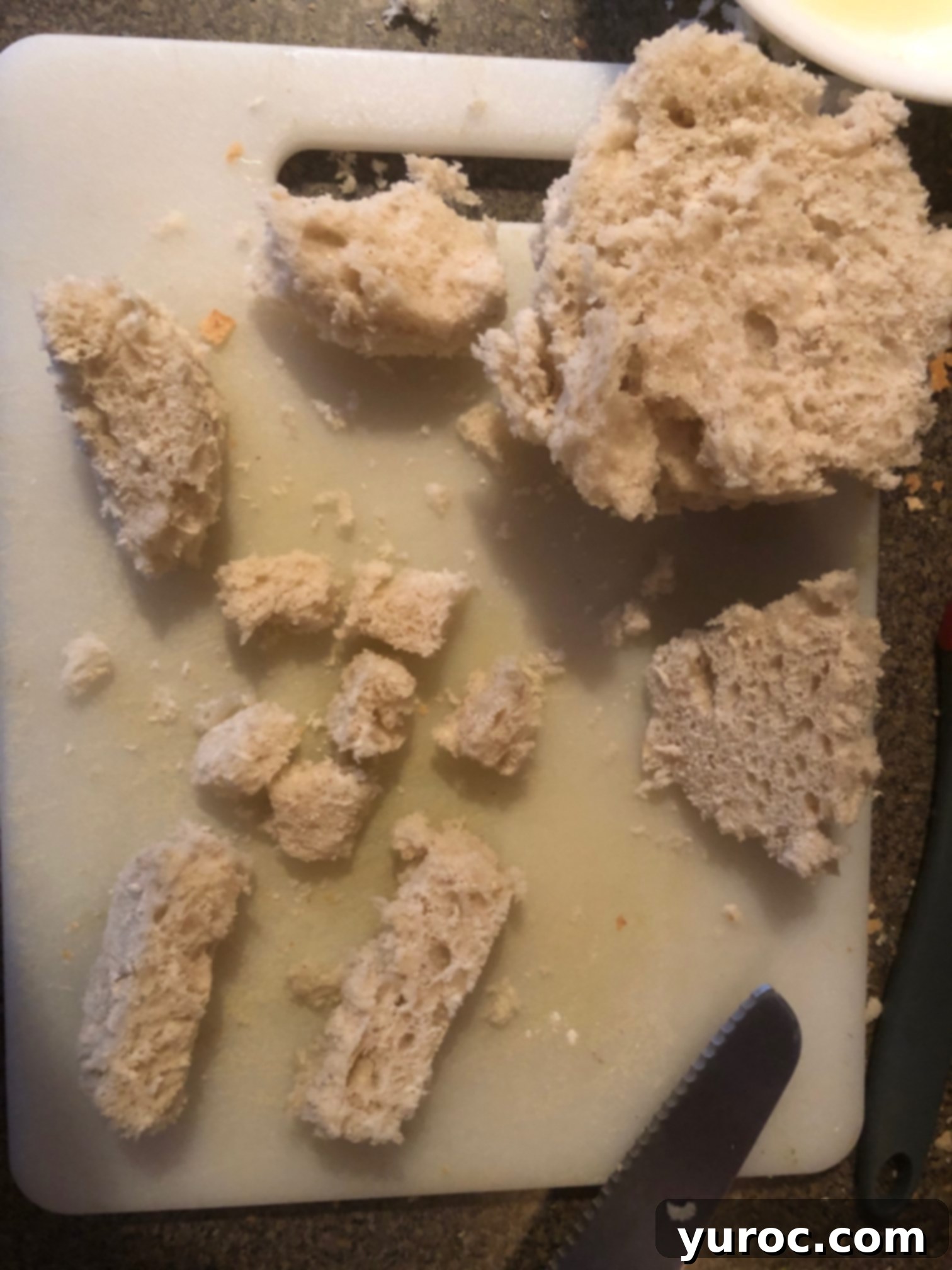 Tuscan Panzanella Pasta Soup 6 The scooped-out bread from a sourdough loaf is being cubed on a cutting board, ready to be made into croutons.