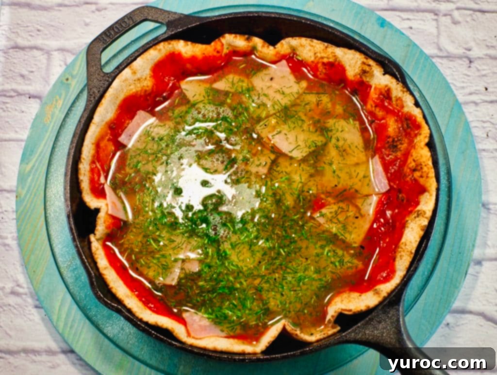 egg white and chive mixture poured on top of ham and pizza sauce on pita crust in cast iron frying pan