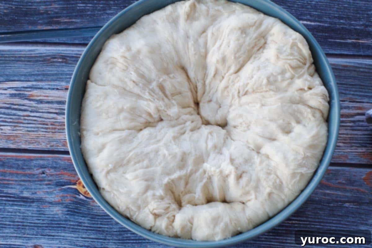 Dough in a bowl after being punched down, showing a deflated state