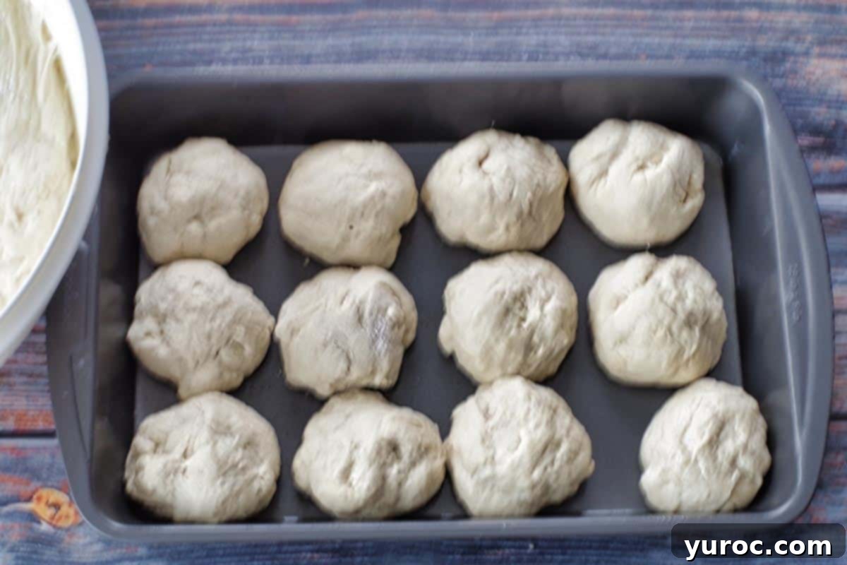 Unbaked dough balls arranged neatly in a metal lasagna pan, ready for final rise