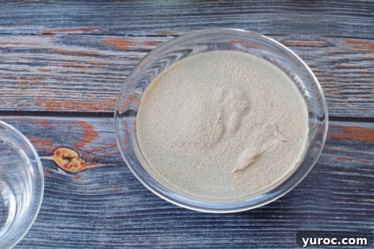 Quick-rise yeast sprinkled over the water and sugar mixture in a glass bowl