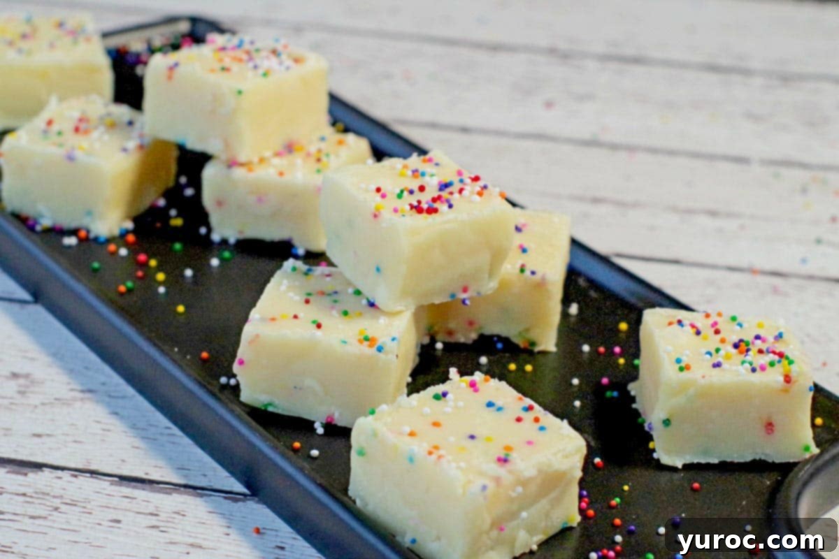Easy Sugar Cookie Fudge 3 Squares of delicious sugar cookie fudge arranged artfully on a sleek black serving platter, resting on a white faux wood surface, ready to be enjoyed.