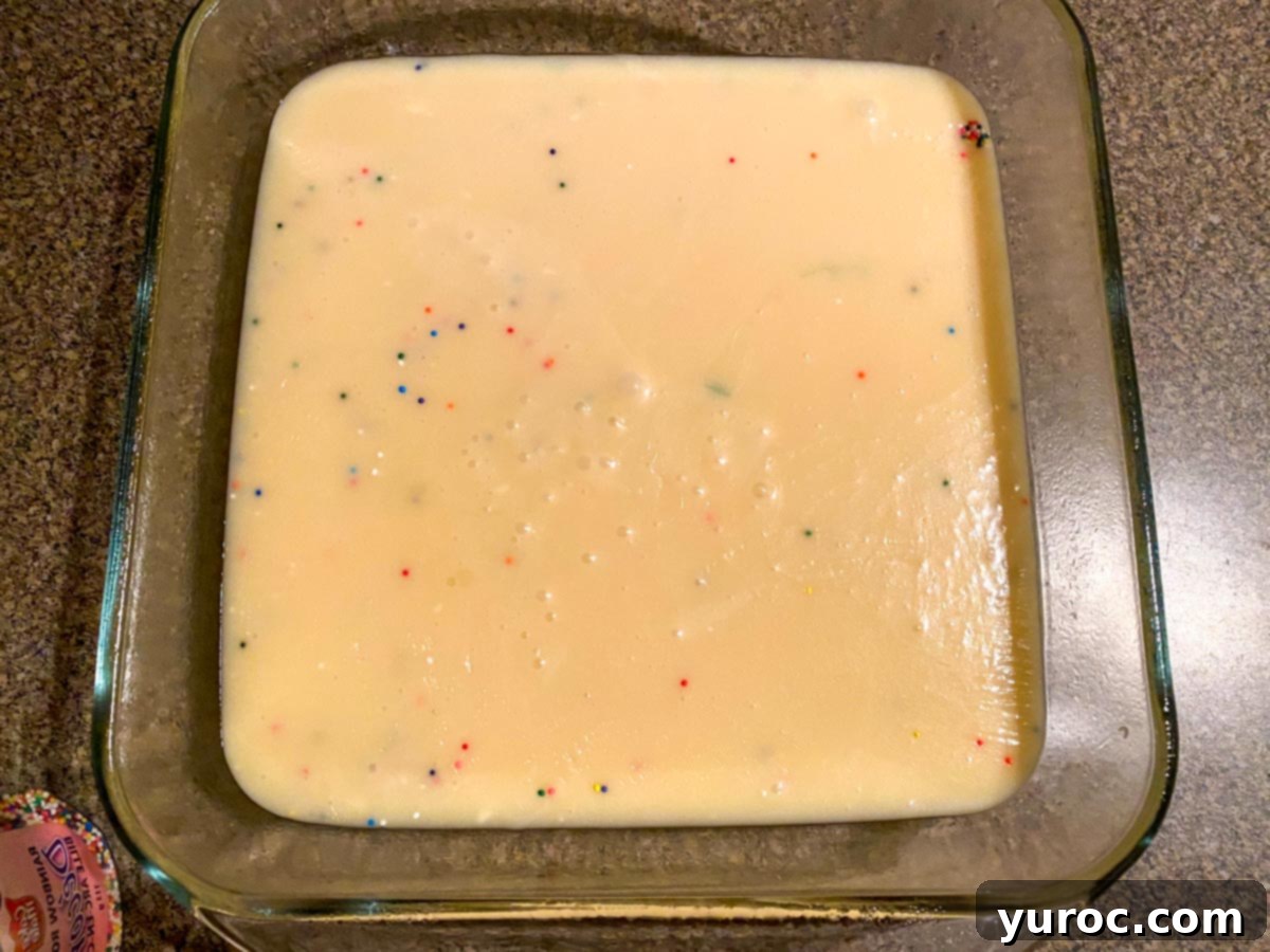 Easy Sugar Cookie Fudge 4 Smooth and creamy sugar cookie fudge batter glistening in a transparent glass pan, ready for the next step in the microwave.
