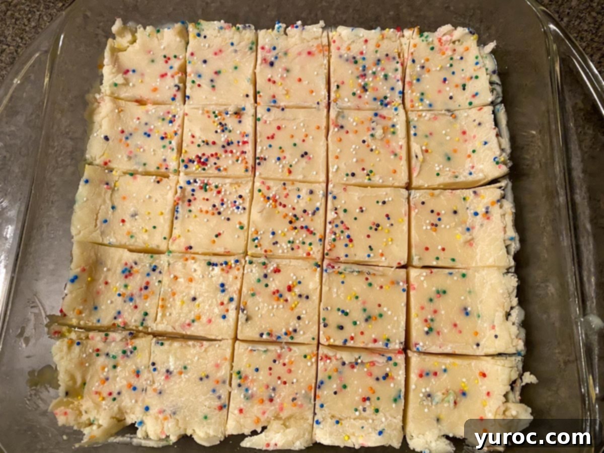 Easy Sugar Cookie Fudge 6 Perfectly set sugar cookie fudge, already cut into uniform pieces, resting neatly within a clear glass pan, ready for serving.