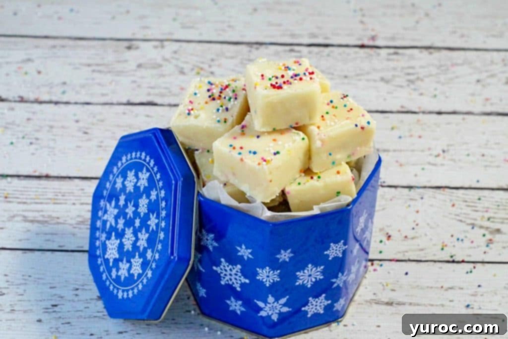 Easy Sugar Cookie Fudge 7 Close-up of vibrant Microwave Sugar Cookie Fudge presented in a charming blue cookie tin, resting on a clean white faux wood surface, ready for gifting or enjoying.