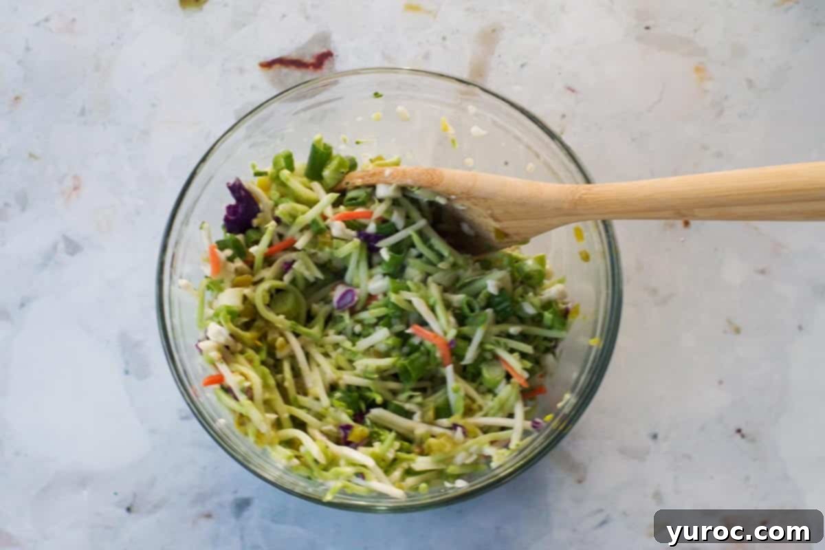 Slaw dressing being poured over the broccoli slaw mixture.
