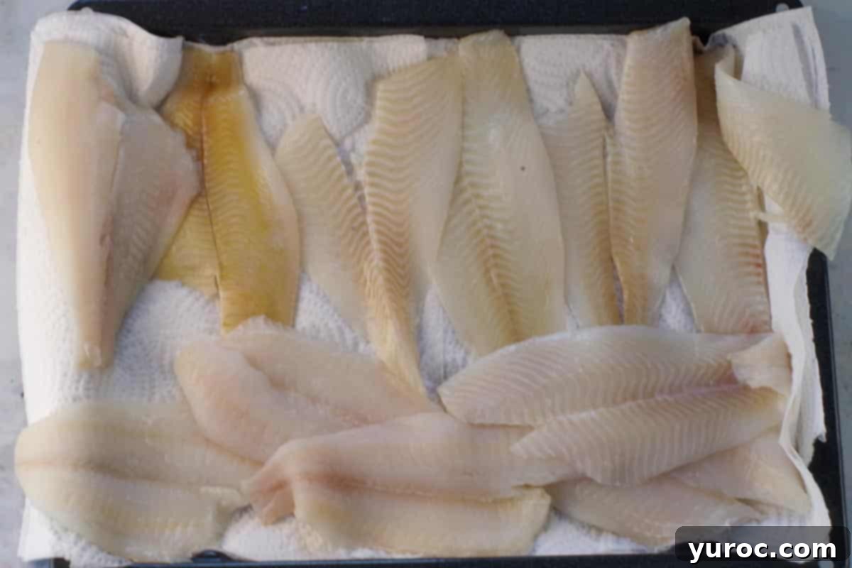 Milk drained from fish, and fish being patted dry with paper towels.
