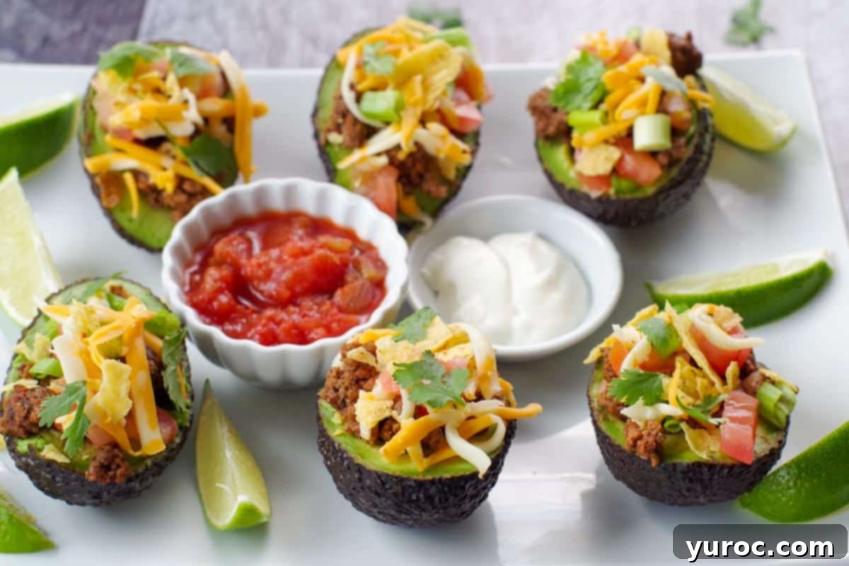 A white tray of vibrant avocado tacos, served with salsa, sour cream, and fresh lime wedges.