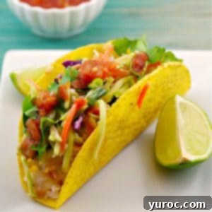 healthy fish taco on a white plate with a wedge of lemon