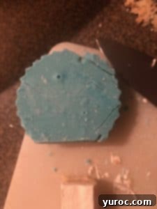 Cutting round shapes from the blue candy-coated Rice Krispie Treats with a fluted cookie cutter.