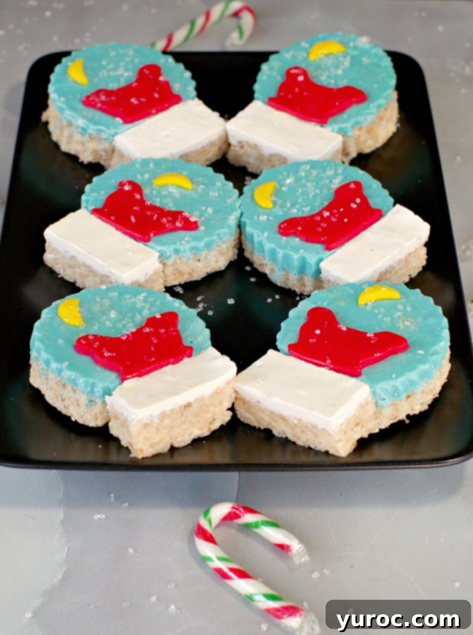 Festive Snow Globe Krispies 3 Snow Globe Rice Krispie Treats arranged on a black tray alongside candy canes, showcasing their festive appeal.
