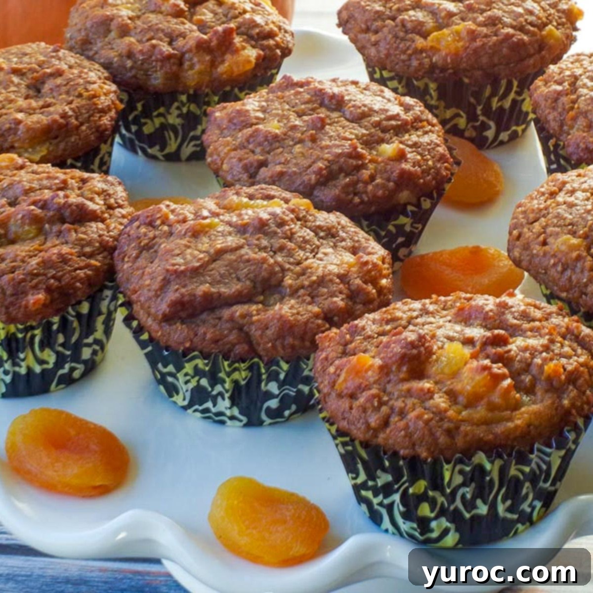 healthy bran pumpkin muffins on a white cake platter with dried apricots