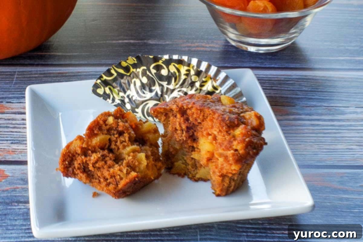 Healthy bran pumpkin muffin split in half,  on a white plate with a muffin liner