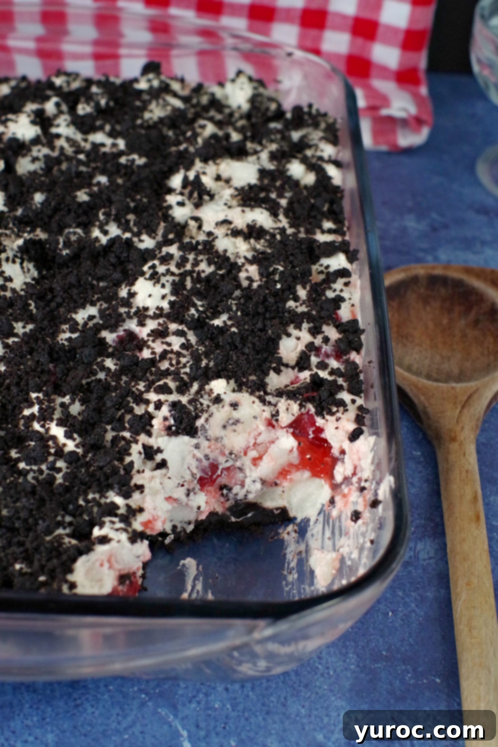 Cherry Cha Cha in a glass pan with a wooden spoon beside it, showing the creamy layers and chocolatey base.