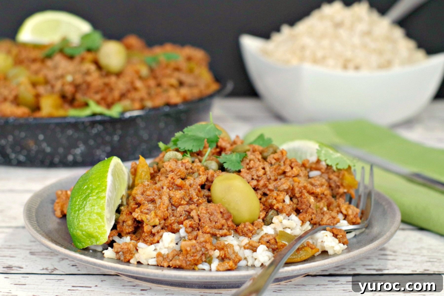 Picadillo over rice with rice and pan of picadillo in background