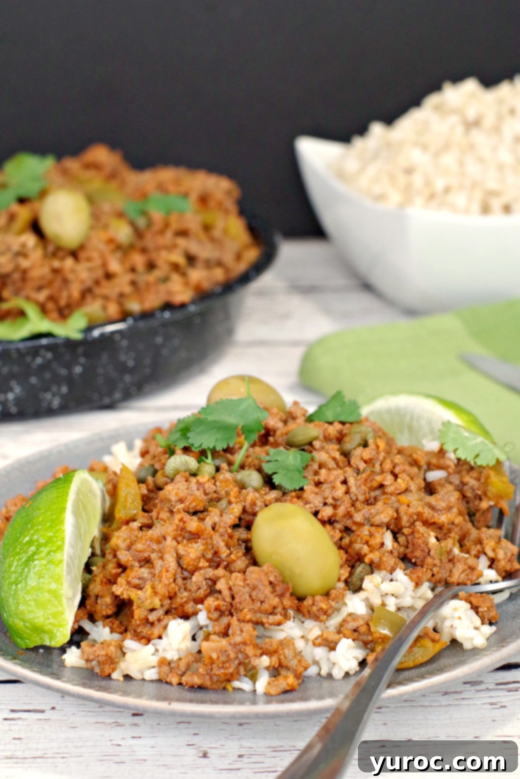 Picadillo over rice with rice and pan of picadillo in background