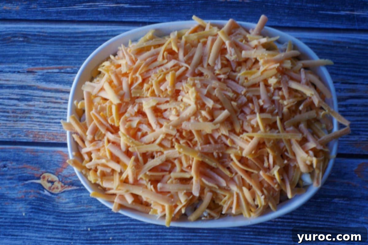 tuna casserole covered with grated cheddar cheese in a white casserole dish