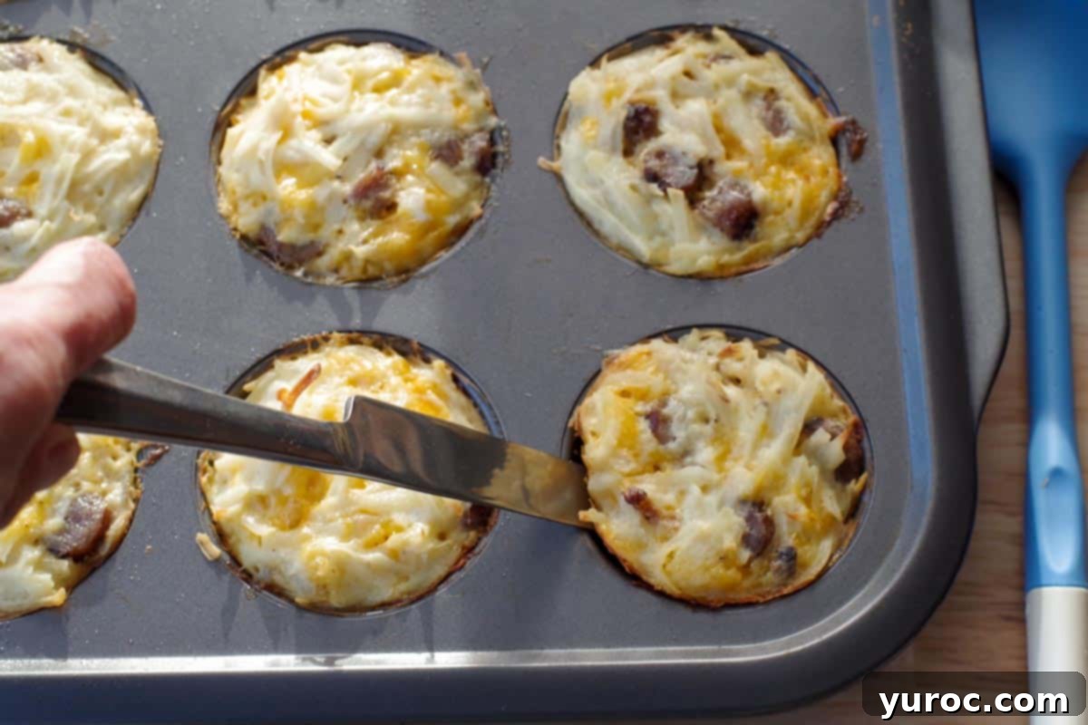 butter knife being run around the edges of the brunch bites to loosen them, while they are still in pan