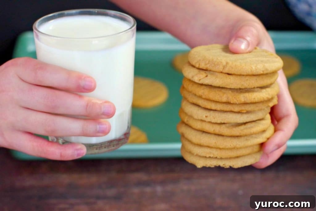 Chunky Peanut Butter and Cookie Butter Cookies 2 hands holding a stack of cookie butter cookie in one hand and a glass of milk in the other