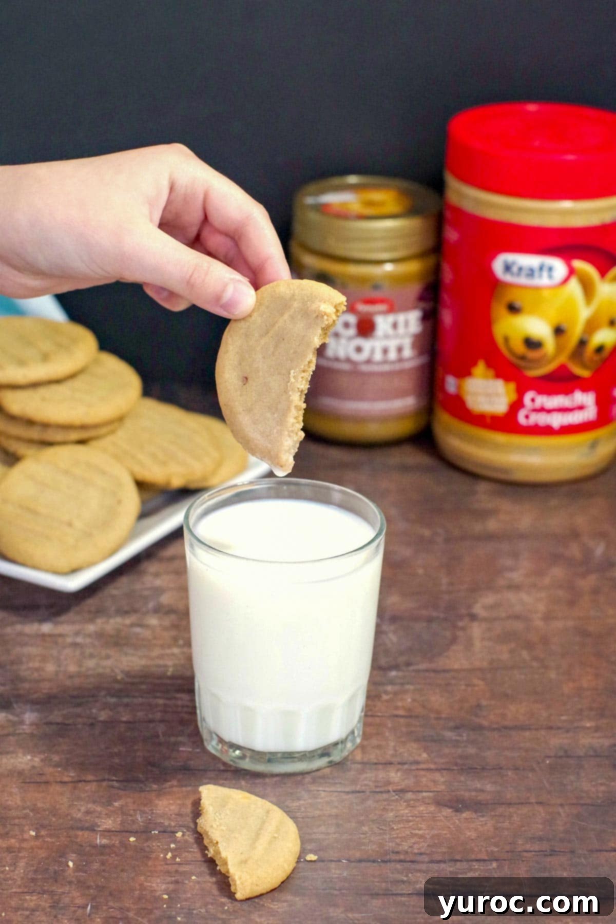 cookie butter cookie being dipped into a glass of milk