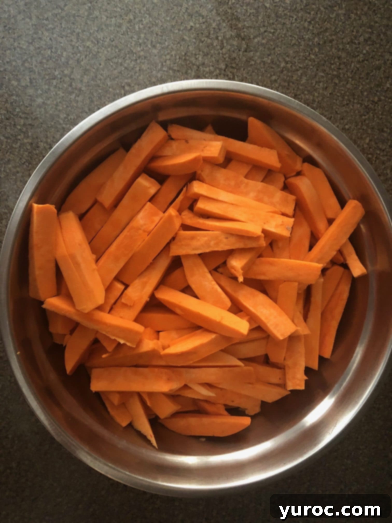 sweet potato fries tossed in bowl with oil and seasoning