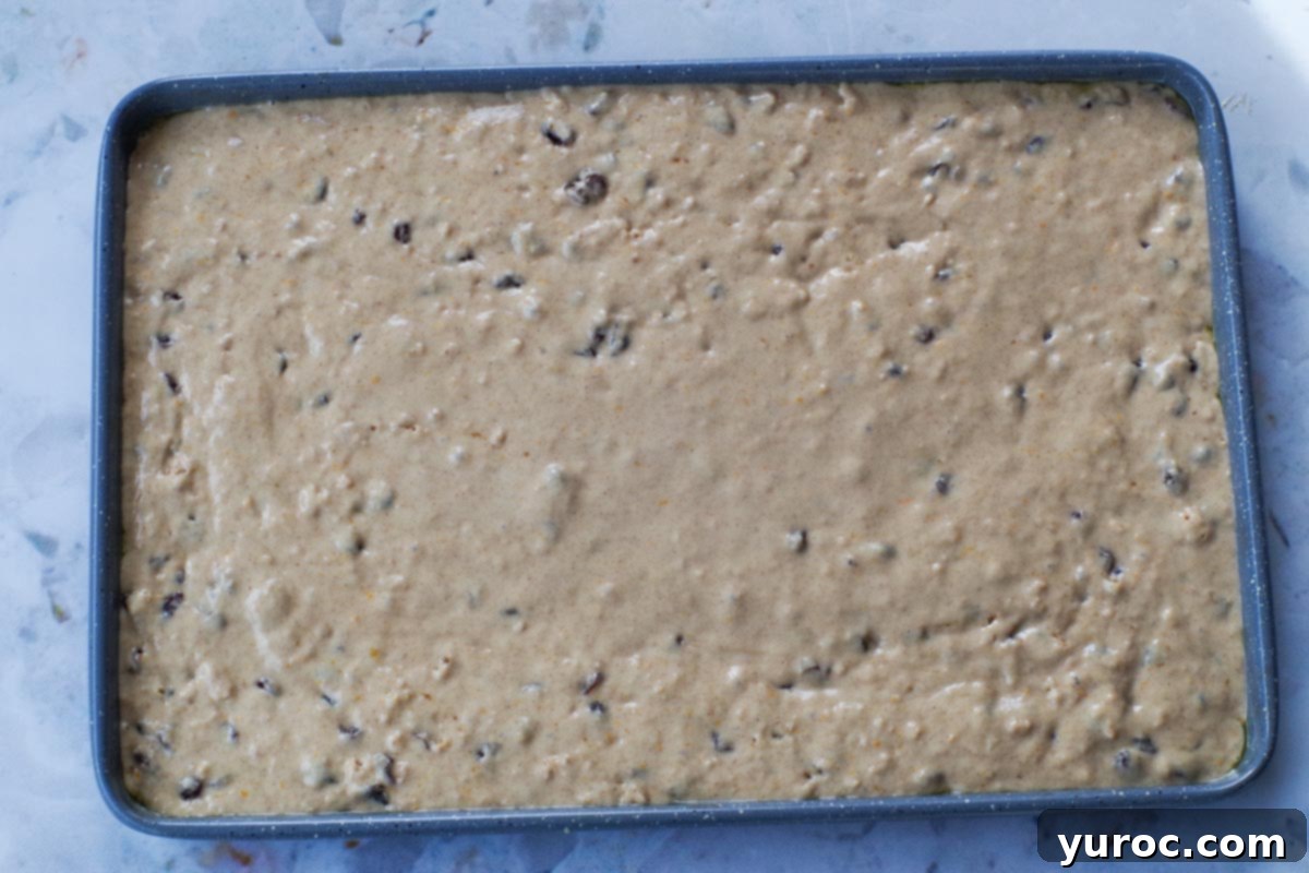 Pancake batter on a sheet pan, now smoothed out after being tapped on the counter a few times, ready for the oven.