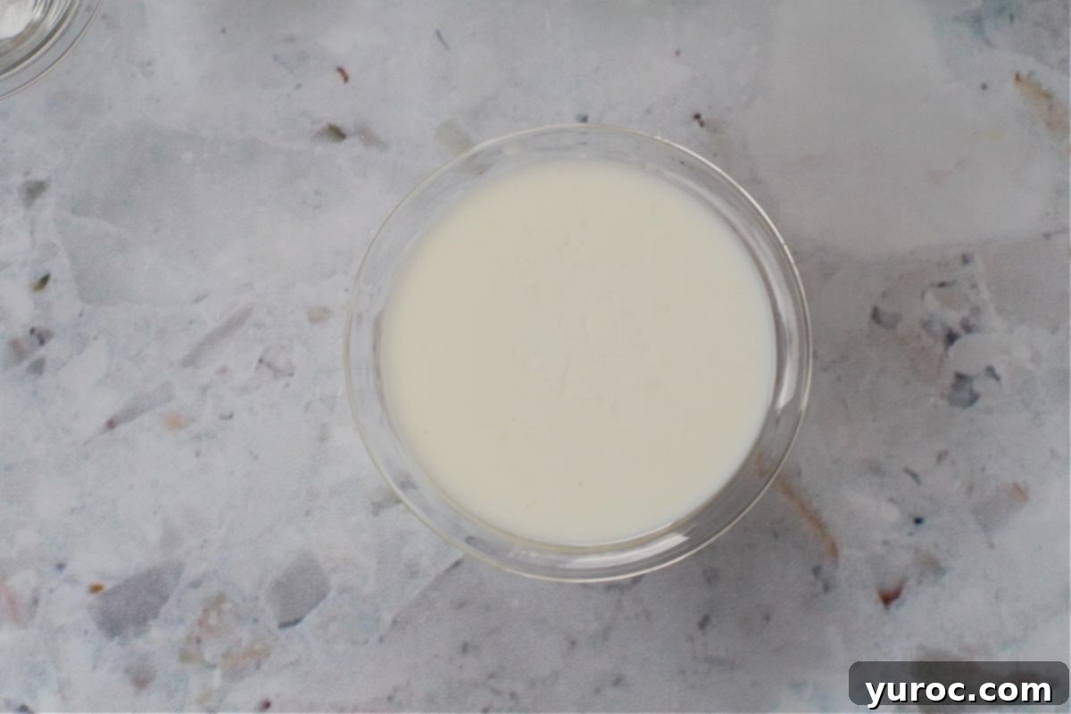 Milk and vinegar mixed together in a small glass bowl, forming a homemade buttermilk substitute.