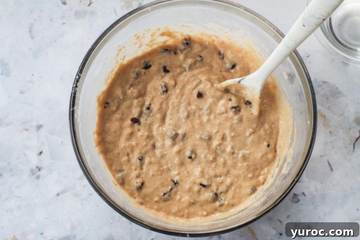 Plump raisins being gently folded into the pancake batter, ensuring even distribution.