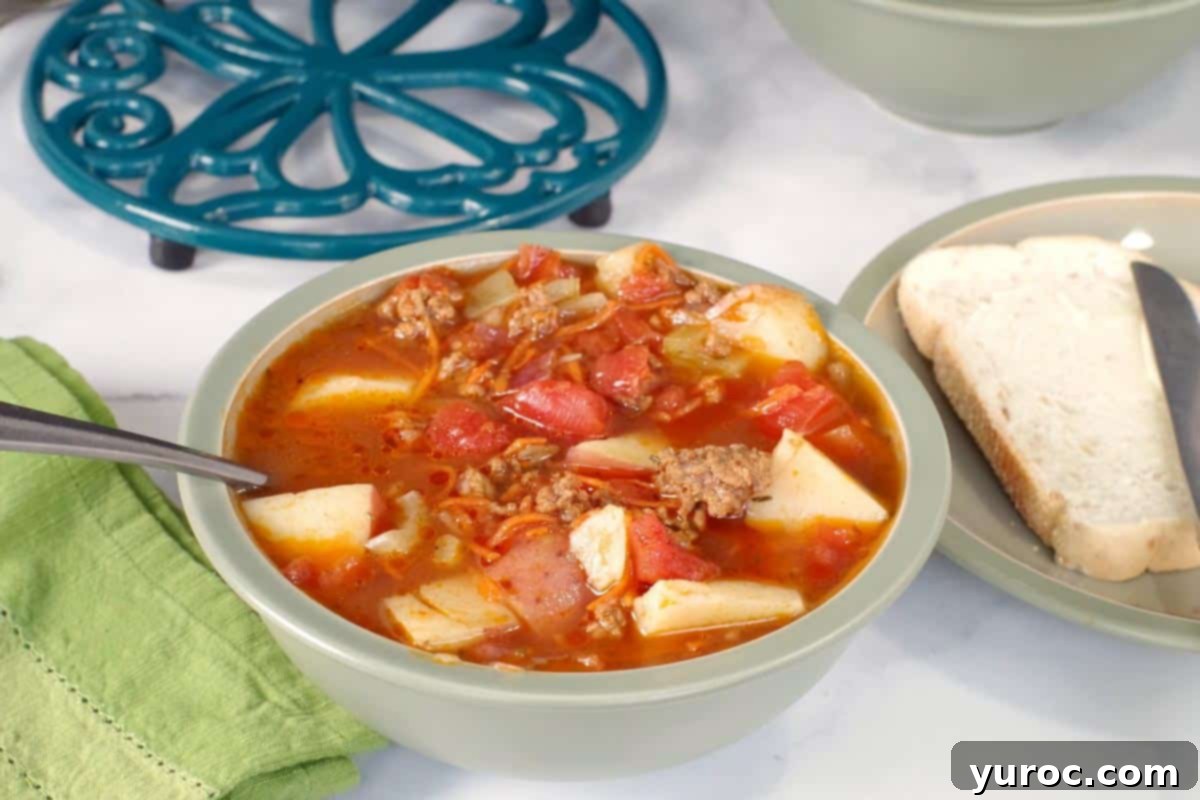 Homestyle Hamburger Potato Soup 2 Hearty hamburger potato soup in a green bowl, with a pot holder in the background, ready to be served and enjoyed.
