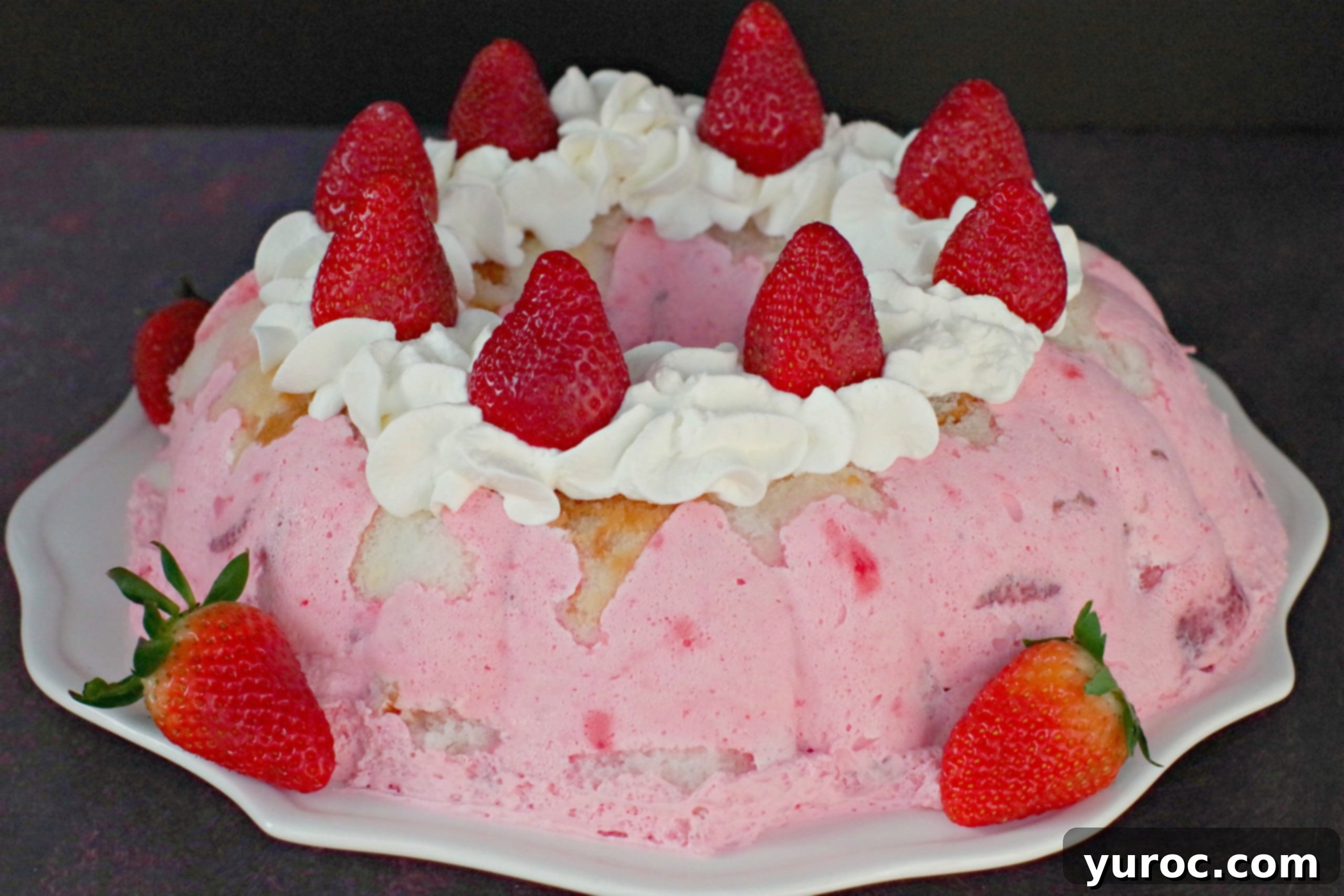 Whole strawberry jello angel food cake on white plate