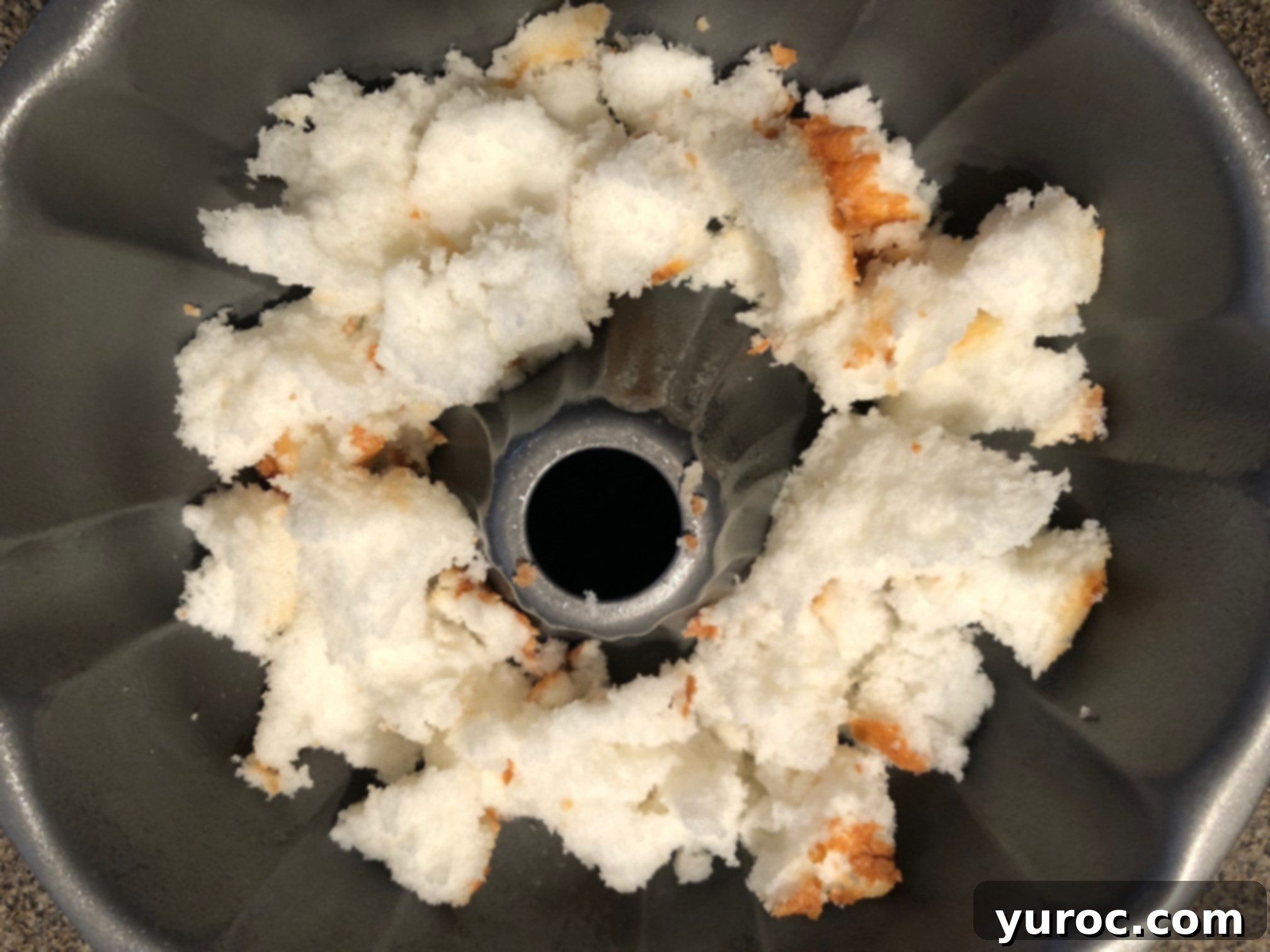 angel food cake torn into pieces in bottom of angel food cake pan