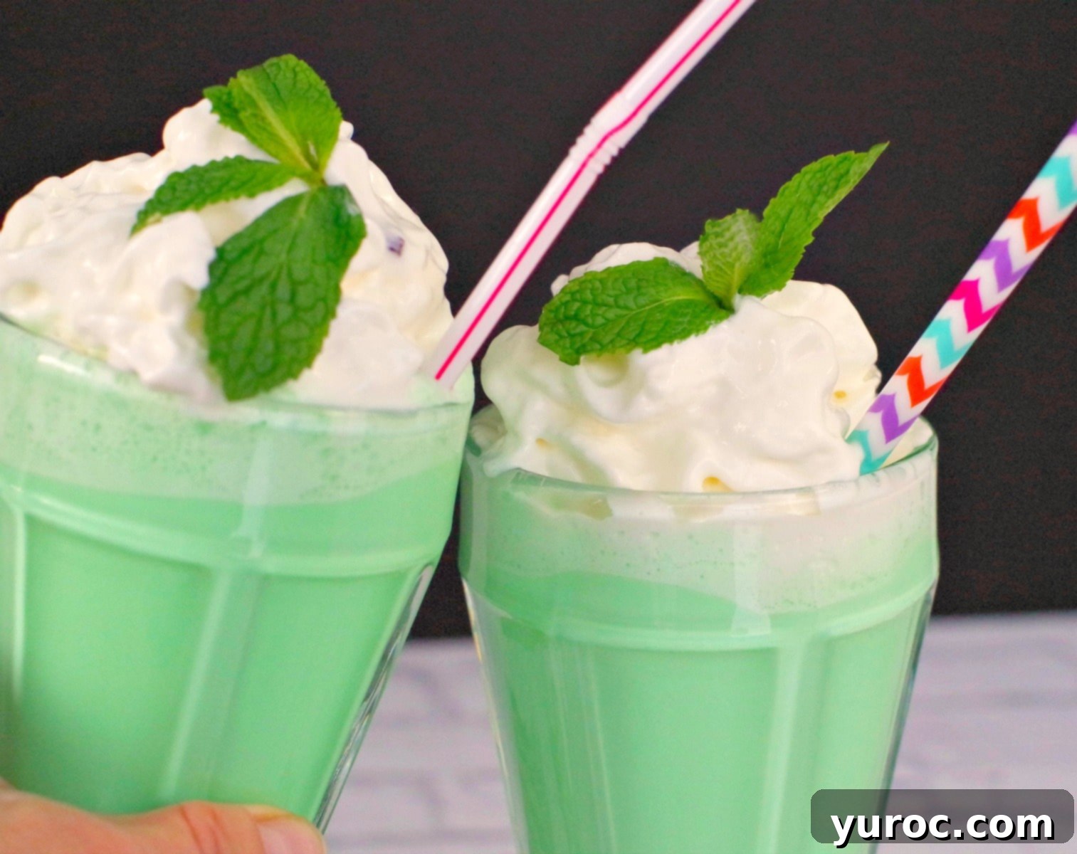 Emerald Grasshopper Mocktail 2 Two glasses of vibrant green Grasshopper Mocktails clinking together, inviting a refreshing sip.
