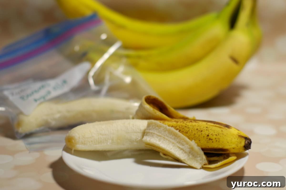 A collage showing peeled banana slices being placed into a freezer-safe bag, demonstrating how to properly freeze bananas for smoothies. Text overlay reads 'Freezing peeled bananas - Foodmeanderings.com'.