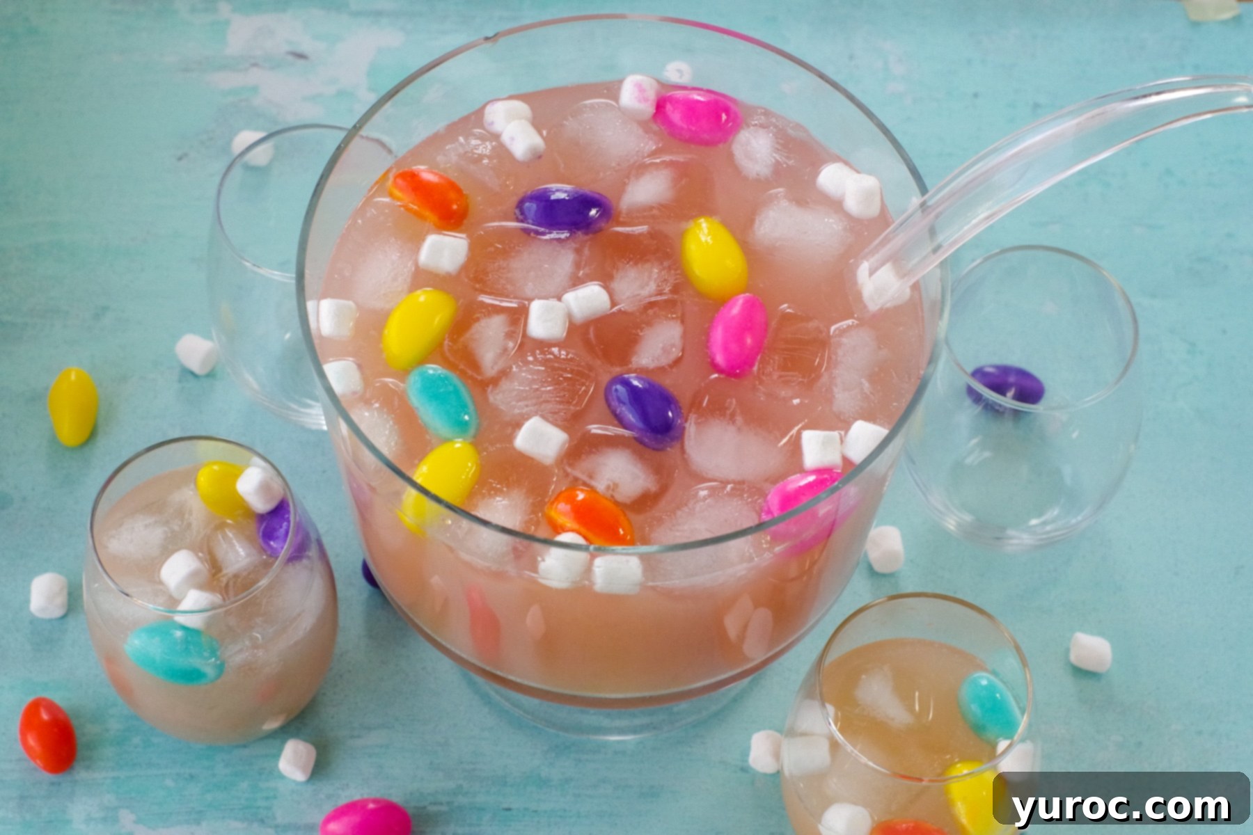 Easter punch in a trifle bowl with glasses around, as well as marshmallow Easter eggs and mini marshmallows