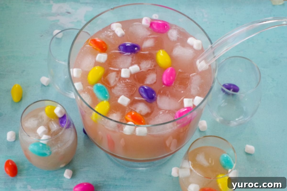 Easter punch in a trifle bowl with glasses around, as well as marshmallow Easter eggs and mini marshmallows