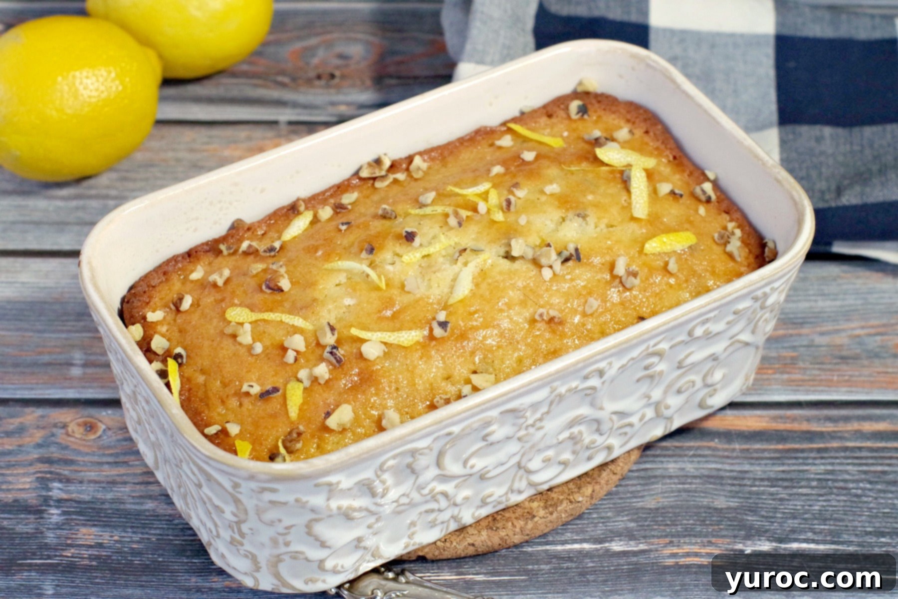Freshly baked lemon loaf in an off-white ceramic loaf pan, cooling