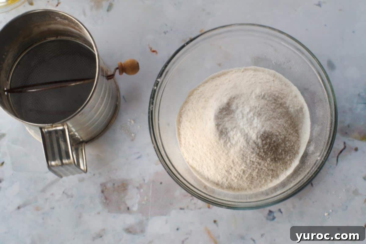 Sifting dry ingredients (flour, salt, baking powder) into a glass bowl