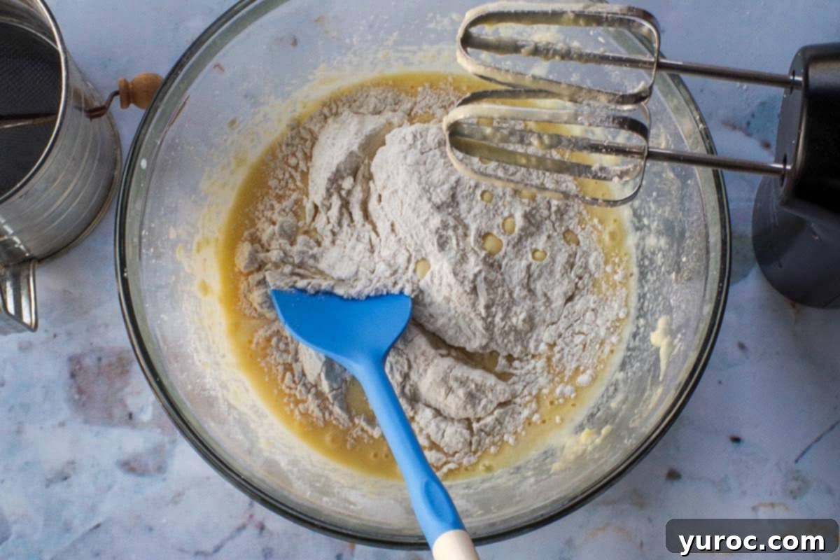 A mix of flour and milk being added alternately to a batter in a glass bowl