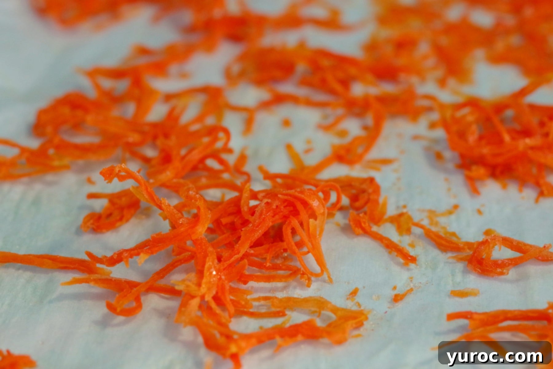 Candied carrot strips spread out on parchment paper to dry