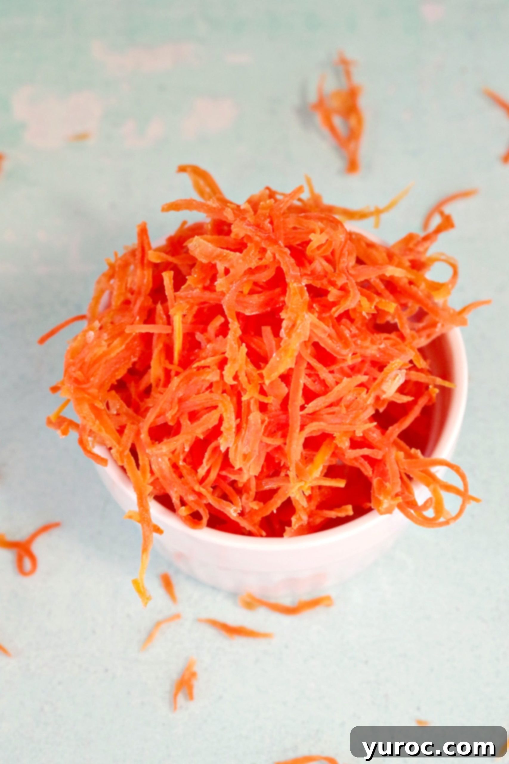 A small white dish overflowing with dried candied carrot strips, ready for serving or garnishing
