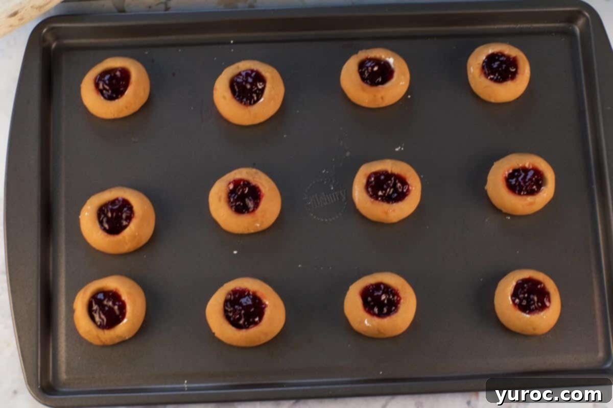 Jam inside cookies ready to go into oven on a baking sheet.