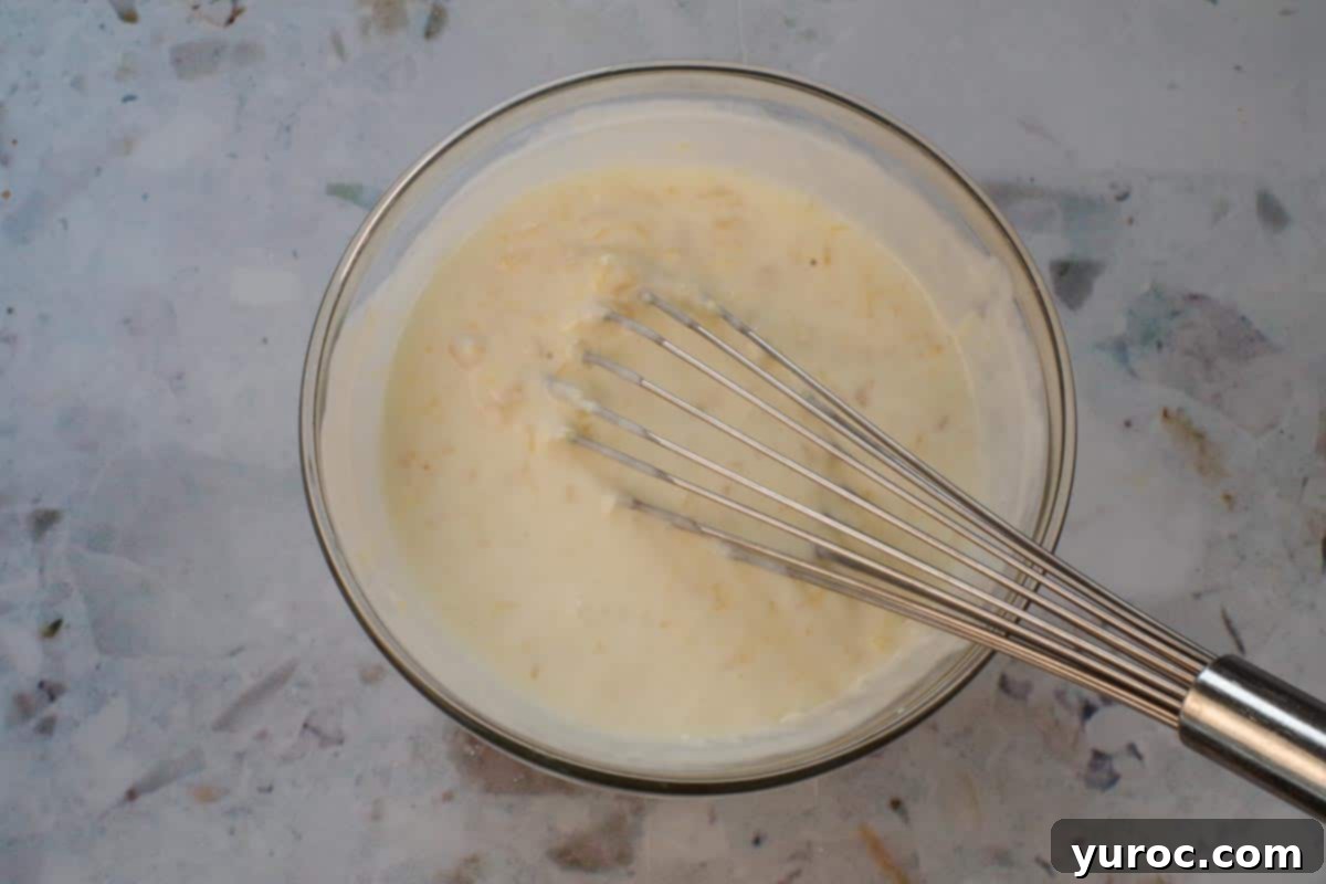 Cool & Creamy Virgin Pina Colada Pops 6 Piña Colada popsicle ingredients being whisked together in a large glass bowl until smooth.
