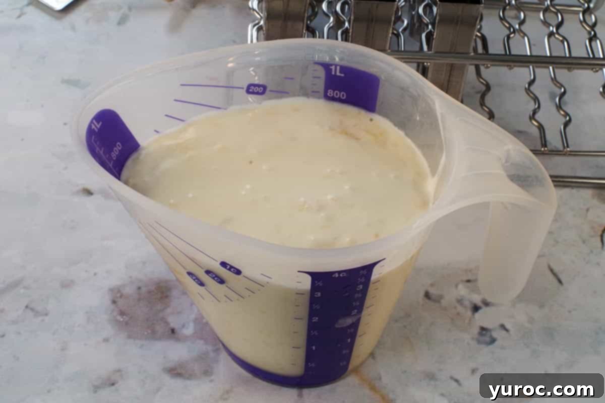 Cool & Creamy Virgin Pina Colada Pops 7 The blended Piña Colada popsicle mixture transferred to a large plastic measuring cup with a pour spout.