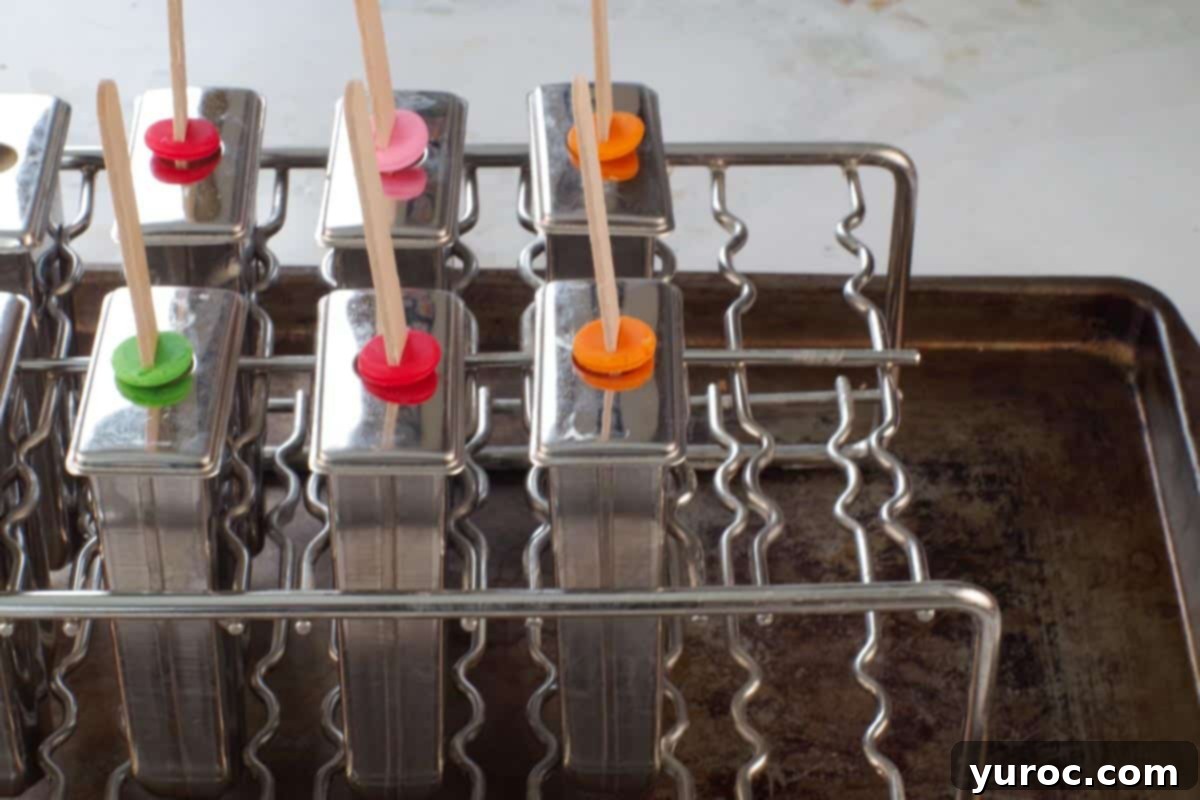 Cool & Creamy Virgin Pina Colada Pops 9 Popsicle molds filled with Piña Colada mixture, set upright on an old sheet pan, ready for freezing.