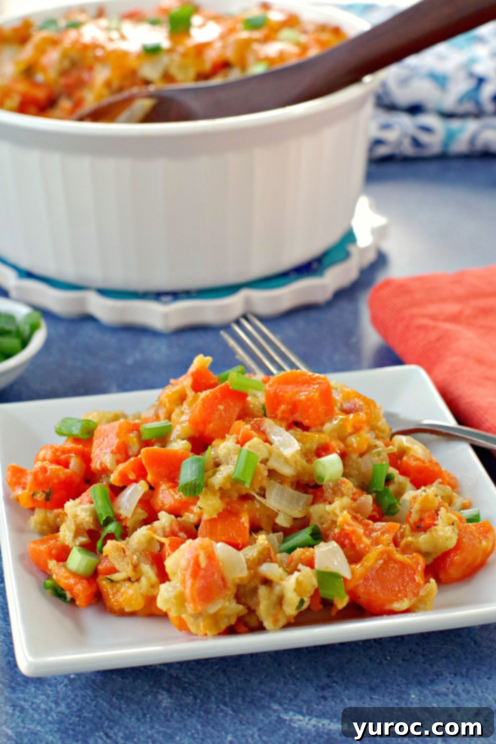 carrot casserole on white plate with white casserole dish full of carrot casserole in the background