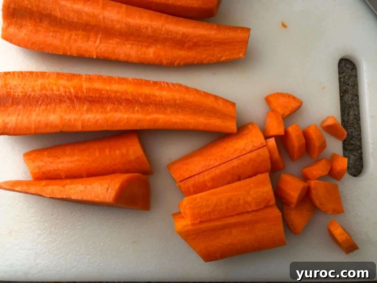 carrots being chopped into small pieces on white cutting board
