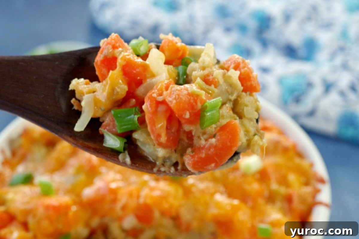 carrot casserole being held up on a dark wooden spoon over a casserole dish full of carrot casserole
