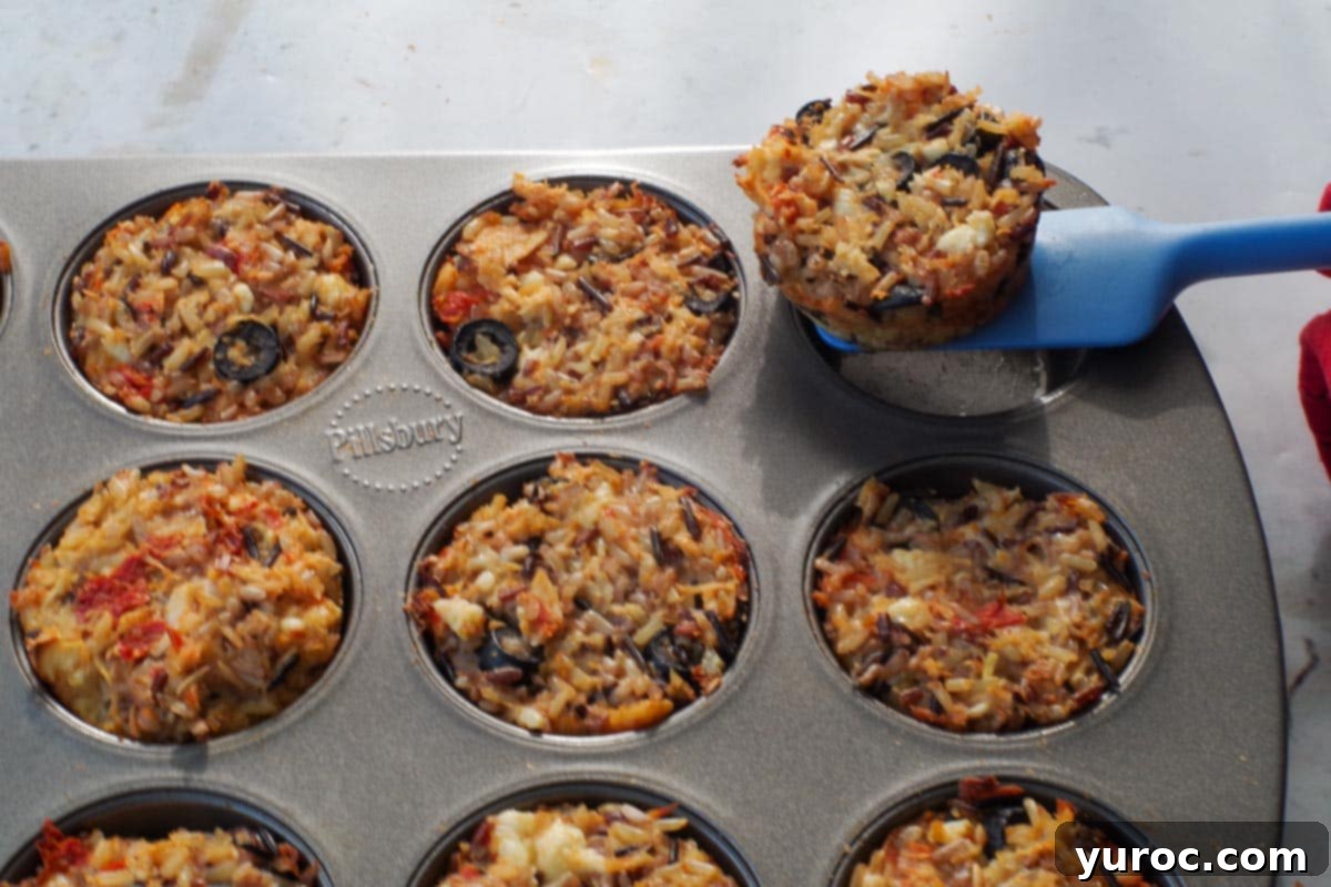 Zesty Mediterranean Chicken Rice Cups 11 A single rice cup being gently removed from a muffin tin with a narrow spatula